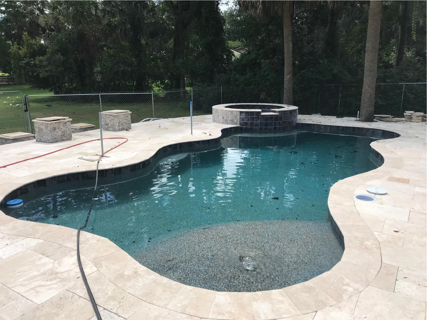 A travertine deck surrounding a free-form swimming pool with stone coping in pinellas county Florida